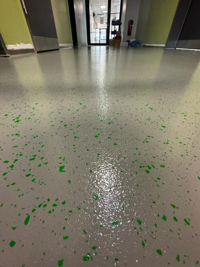 Grauer Boden mit grünen und dunklen Einstreuungen